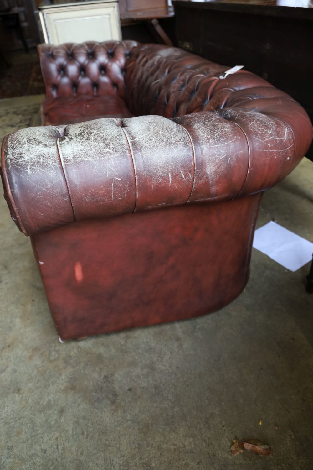 A three seater Chesterfield settee covered in deep-buttoned burgundy hide, length 210cm, depth 90cm, height 76cm